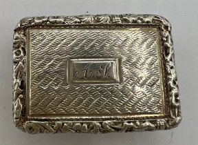 A hallmarked silver vinaigrette with engine turned decoration, cast foliage border and monogrammed