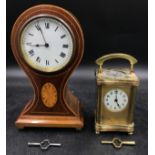 A mahogany inlayed balloon mantle clock on brass ball feet with circular white dial with roman