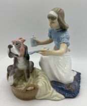 A Lladro Porcelain figure group of a kneeling girl administering medicine to a sick dog in a basket,