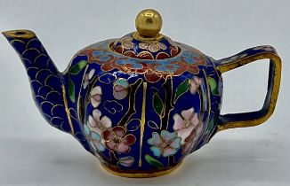 A miniature cloisonné teapot with floral decoration on blue ground. 5cm h x 8cm w.