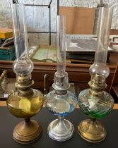 Three vintage oil lamps with chimneys, tallest including chimney 52cm h.
