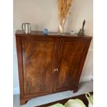 A two door mahogany cupboard on later bracket feet 129cm h x 120cm w x 27cm d