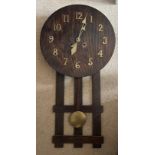 An oak Arts and Crafts wall clock with brass pendulum and 80cm h. Brass hands and numbers.