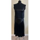 A 1920's black satin sleeveless evening dress with split to waist at back and overlay to top,