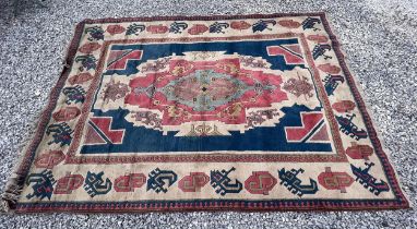 A large vintage wool carpet in cream, reds and blues with motifs and coats of arms. 317 x 226cm.