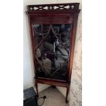 A mahogany corner cupboard with single glazed door and carved cornice to top on later oak base