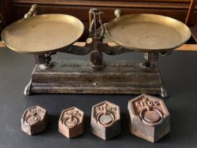 Forge iron weighing scales with brass pans and four weights.