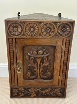 A heavily carved, early 20thC oak single door corner cupboard. . With single shelf to interior. 38 w
