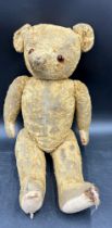 An early 20th century well loved straw filled teddy bear. Approximately 51cm high.