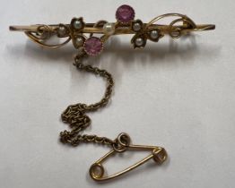A 15 carat gold bar brooch set with seed pearl and rubies with safety chain. 2.6gm.