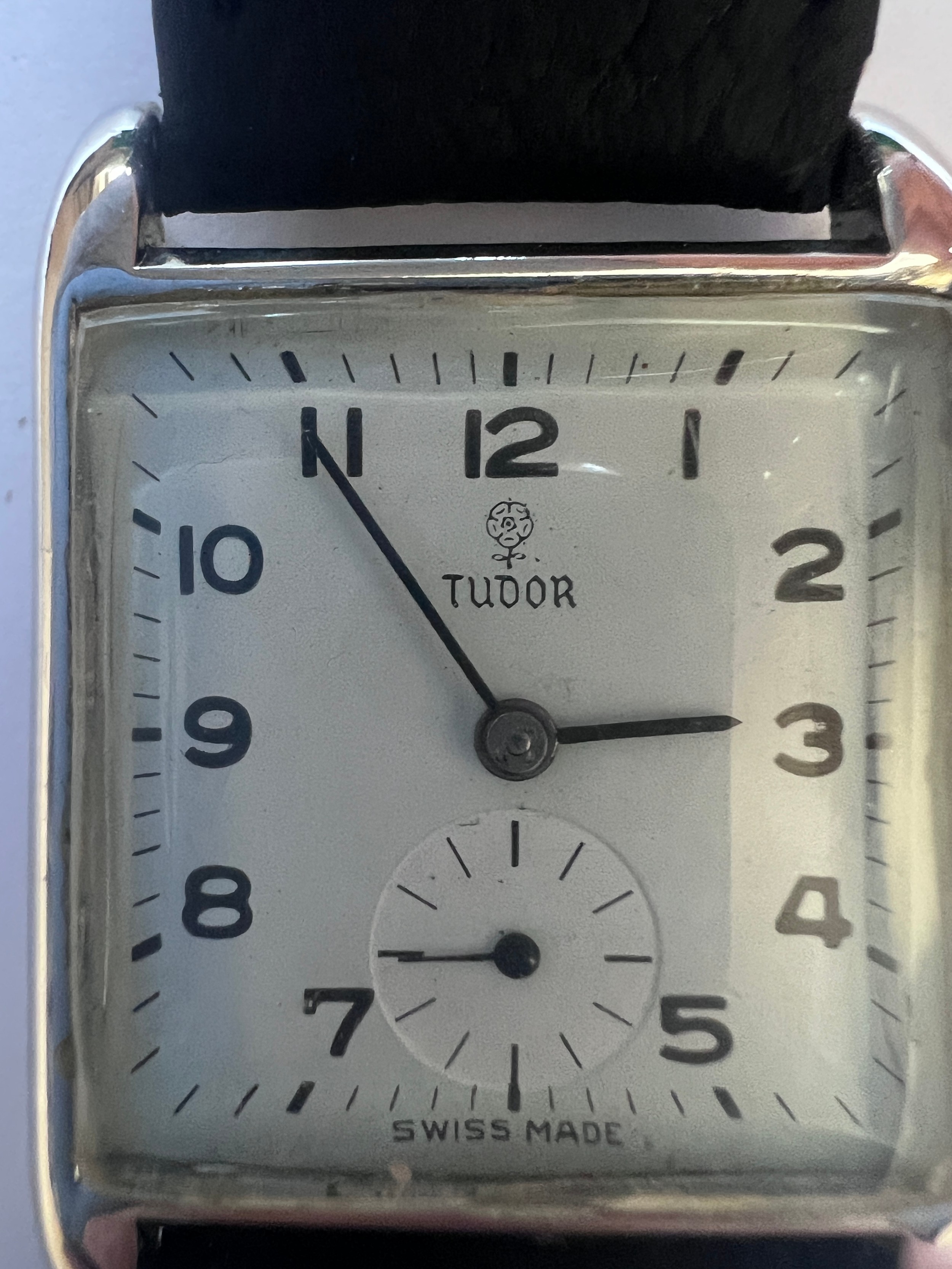 A vintage Rolex Tudor hand winding wristwatch on black leather strap, chrome case and ivory dial