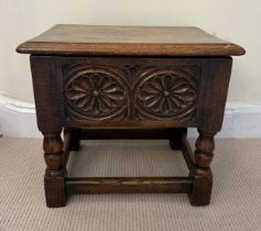 A heavy oak stool with lift up lid and carving to the front and sides. 42.5w x 33 d x39cm h.