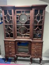 A very highly carved hardwood display cabinet/ bookcase, three glazed doors over a base of drawers