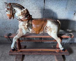 An early 20thC skin covered wooden rocking horse with leather saddle and bridle. Horse hair tail.
