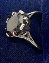 An 18 carat white gold ring set with dark red stone. Size P/Q.