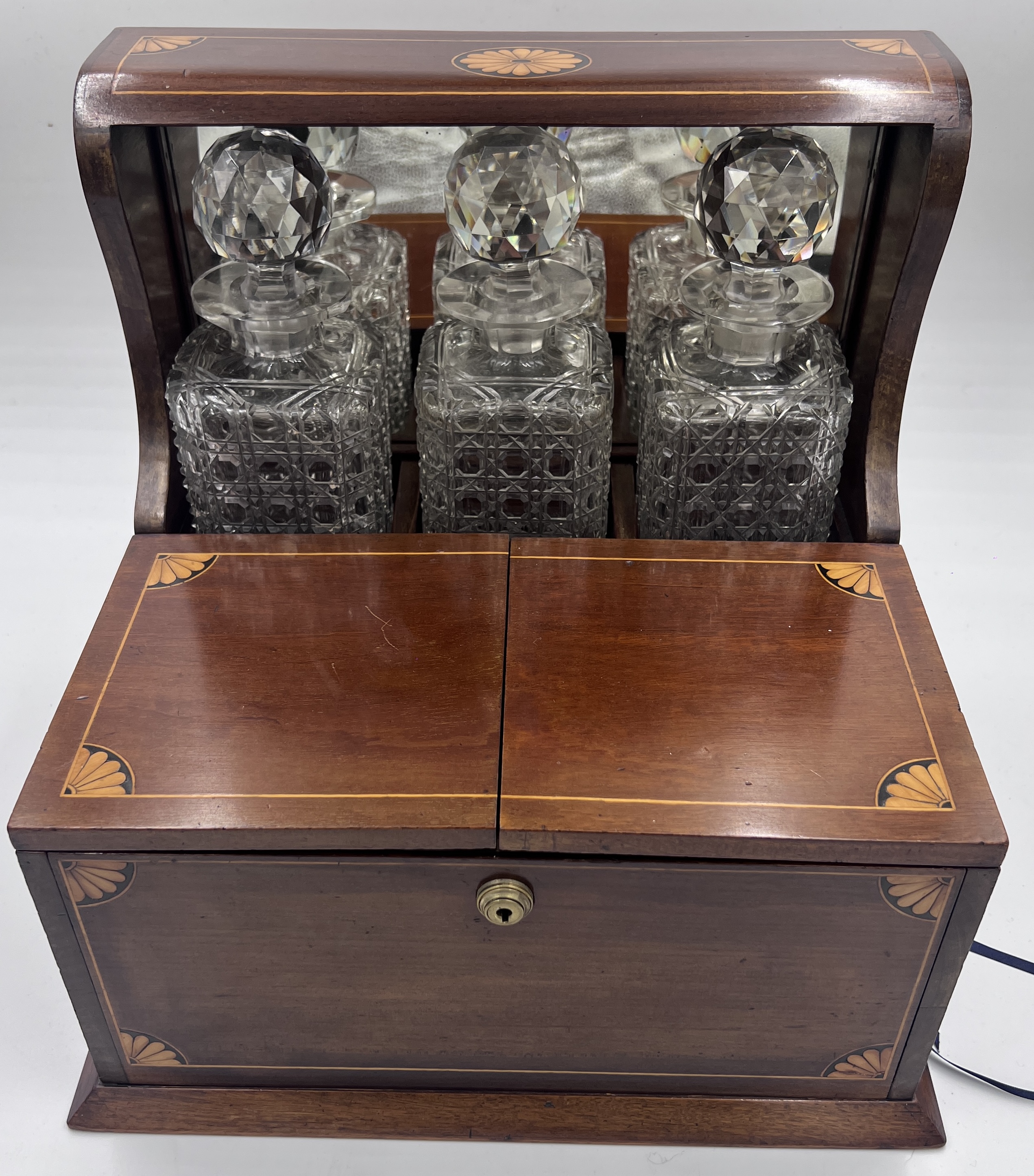 An Edwardian mahogany inlaid cut glass tantalus and games box containing cigar cutter, silver plated