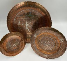 Three Egyptian copper and white metal wall plates, largest 35cm d.