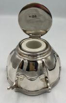 A silver inkwell with pen rest London 1907, maker Edward Barnard & Sons. 9.5 cms x 9.5cm at base.