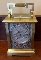 Brass carriage clock with visible escapement, silver filigree decoration and repeater mechanism.