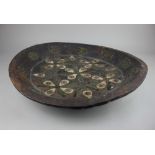 A Moroccan carved wooden dish, with bone inlaid pattern and applied metal scrollwork 54.5cm