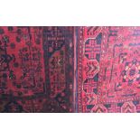 A Pakistani hand-knotted wool rug, red ground, with floral design, label to underside 198cm by 81cm,
