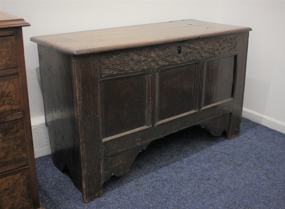A small oak coffer the hinged rectangular top above three panel front with carved frieze, on bracket