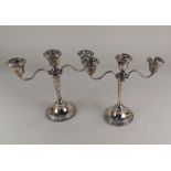 A pair of Elizabeth II silver three branch candlesticks on loaded bases, maker Adie Brothers Ltd,