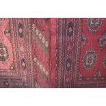 A pair of Turkoman type rugs, red ground, each with three rows of medallions within multiple borders