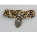 A gold decorated and plain oval and bar link gate bracelet detailed 9c on a gold heart shaped