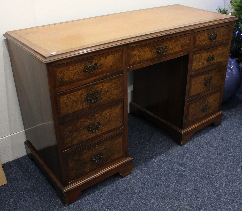 A reproduction walnut desk, the rectangular top with brown leather inset above an arrangement of