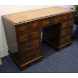 A reproduction walnut desk, the rectangular top with brown leather inset above an arrangement of