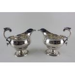 A pair of George VI silver pedestal sauce boats with flying scroll handles and gadrooned edges,