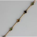 A gold and vari-coloured gem stone bracelet in a curved bar link design, collet set with oval cut