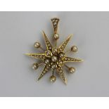 A gold and seed pearl pendant designed as a starburst with a flower head motif at the centre,