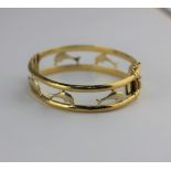 A gold oval hinged bangle pierced with dolphin motifs on a snap clasp detailed 750, 23g