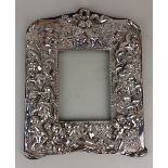 A modern silver photograph frame rectangular aperture with arched frame on blue cloth backing,