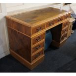 A modern yew wood pedestal desk, with leather inset rectangular top above an arrangement of nine
