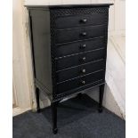 A black painted music cabinet, with fret cut border enclosing six drawers with drop-down fronts,