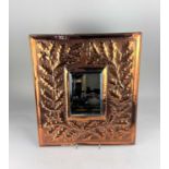 An Arts and Crafts copper rectangular wall mirror decorated in light relief with oak leaf foliage,