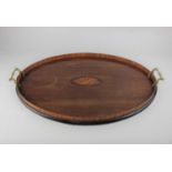 A mahogany oval two handled tray inlaid with central shell motif