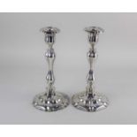 A pair of Rococo style silver plated candlesticks with baluster stems on raised shaped circular