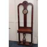 A Victorian mahogany hall stand with central circular mirror flanked by coat hooks, above hinged
