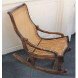 An early 20th century rocking chair with cane back and seat