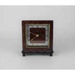 An Asprey of London burrwood mantle clock with square dial and silvered chapter ring on scroll feet,