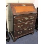 A George III oak bureau the fall front with inlaid panel, enclosing a fitted interior of pigeon
