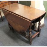 An oak gateleg table the oval top with two drop flaps on turned supports 129cm fully extended