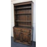 A George III style oak bookcase on cupboard with three shelves and boarded back on base with two
