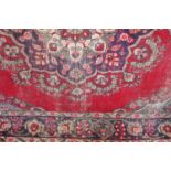 A red ground carpet, possibly Indian, with central floral medallion within multiple borders 287cm by