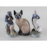 Three Royal Copenhagen porcelain figures comprising a Siamese cat and two figures