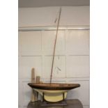 A wooden model pond yacht with single detachable mast, 101cm wide, on stand, with sails and